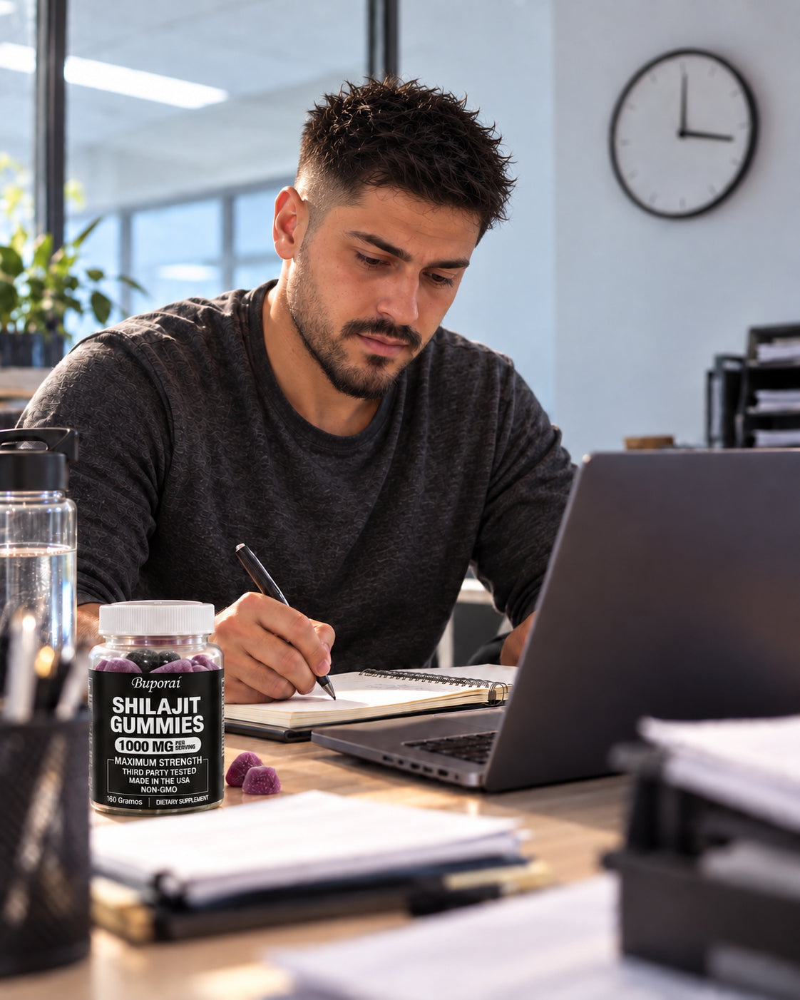 Hombre concentrado trabajando en su escritorio con un frasco de Shilajit al lado